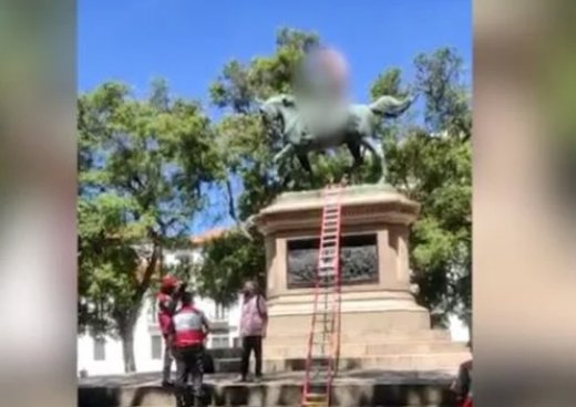 Homem sobe em estátua, fica pelado e exige ser vacinado